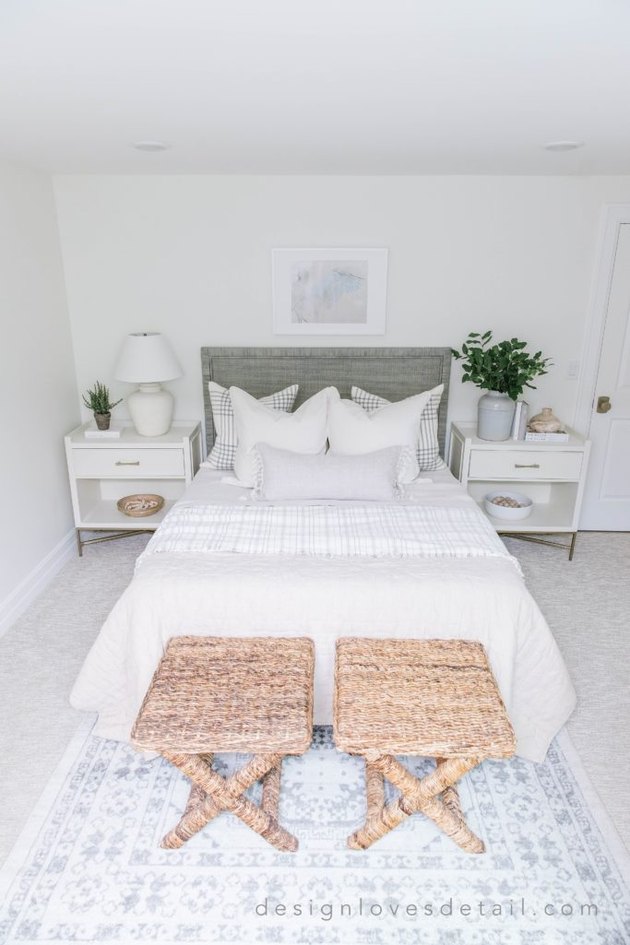 Modern coastal bedding idea with linen bedding and seagrass stools