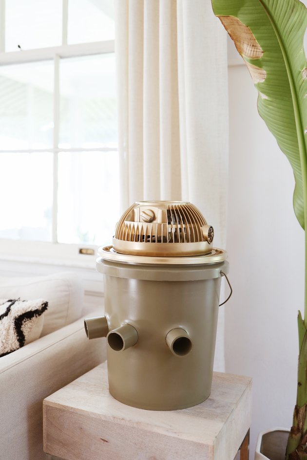 Green and gold portable bucket air conditioner on an end table next to a couch
