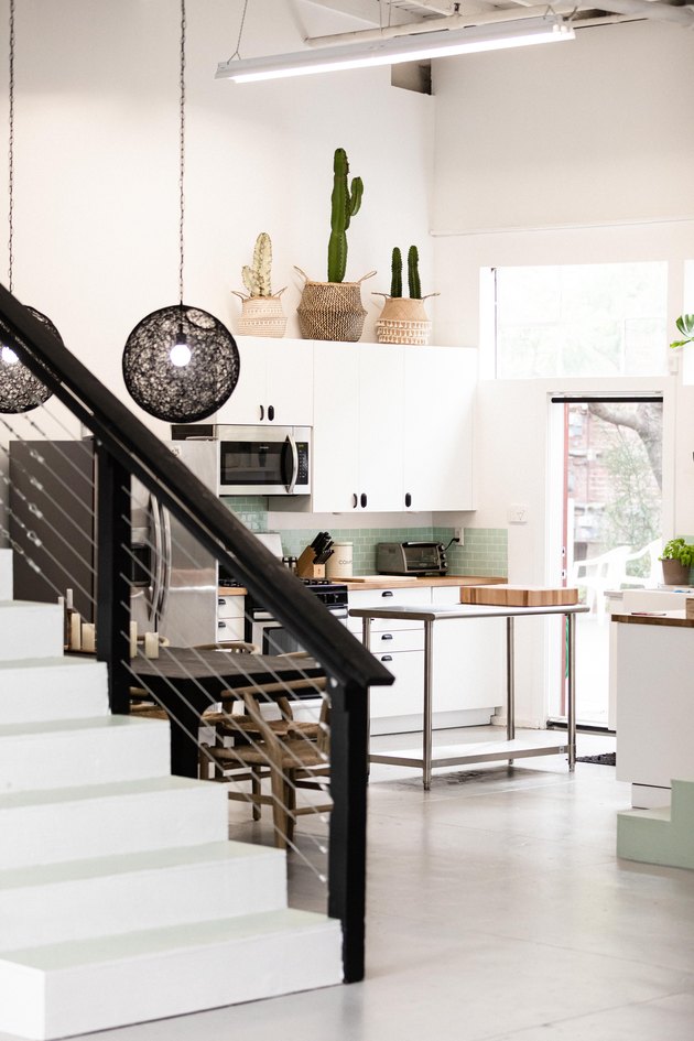Black and white painted stair rails leading to minimalist kitchen.