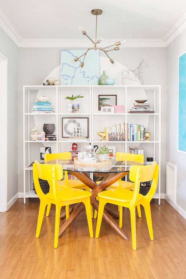 small dining room with glass top dining table and yellow dining chairs