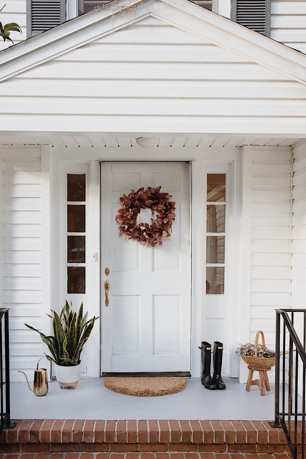 Freshly painted concrete porch with gray paint, wreath on door, entry rug, planter, boots and watering can
