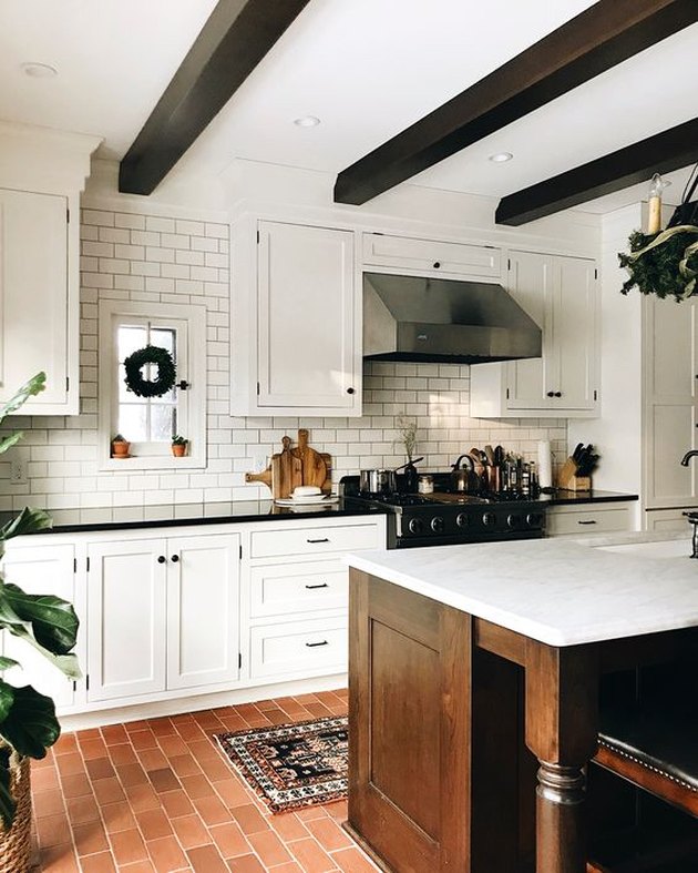 modern farmhouse kitchen with wood ceiling beams and brick flooring