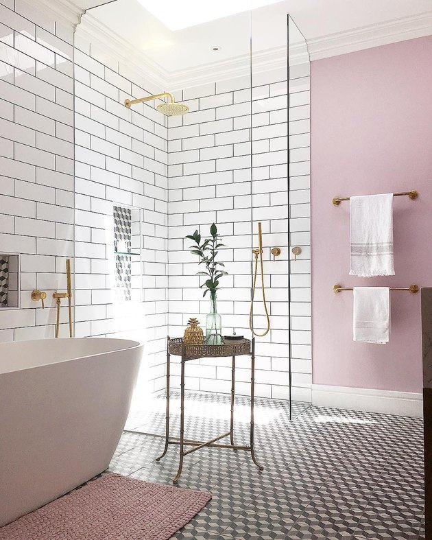 sunset-hued pink bathroom with subway tile on walls and freestanding tub