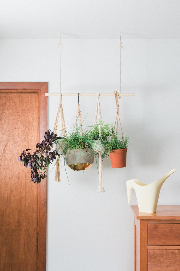 Slip the hanging potted herbs onto the dowel rod between the rope.