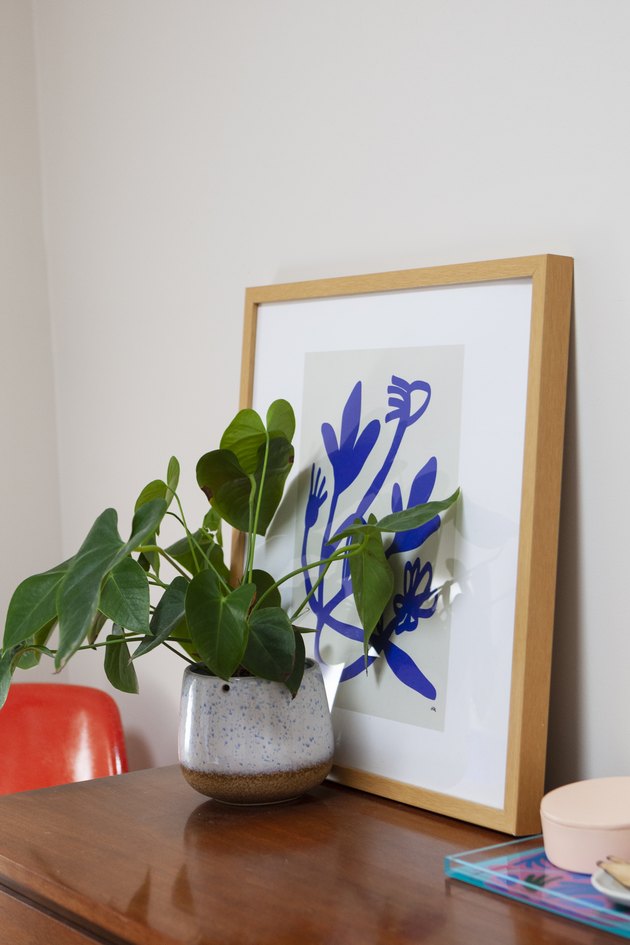 Plant in front of blue art on bedroom dresser