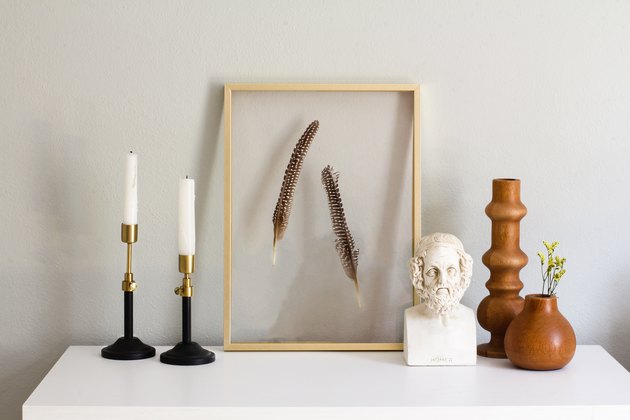 Target Decor: Black and gold candlesticks, framed feathers, and wood vases on entry table