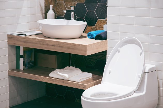 Modern spacious bathroom with bright tiles with toilet and sink. Side view