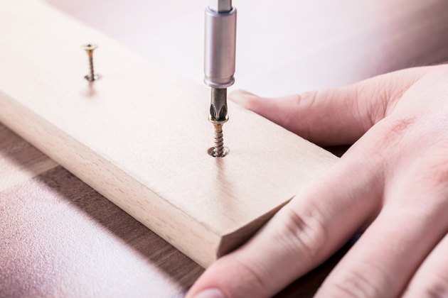 Craftsman Driving A Screw Into A Piece Of Wood