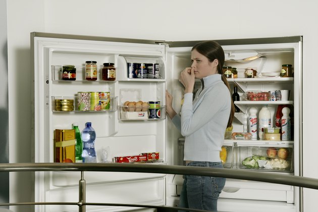 Young woman standing by refrigerator, side view