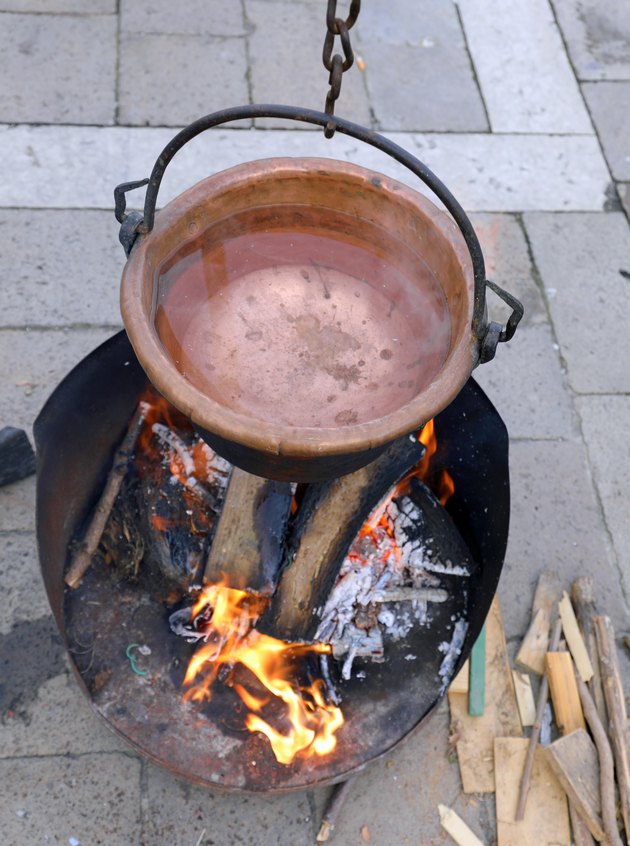 Cauldron with boiling water and a large wood fire