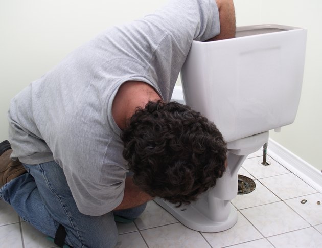 Plumber at work, man installing new toilet