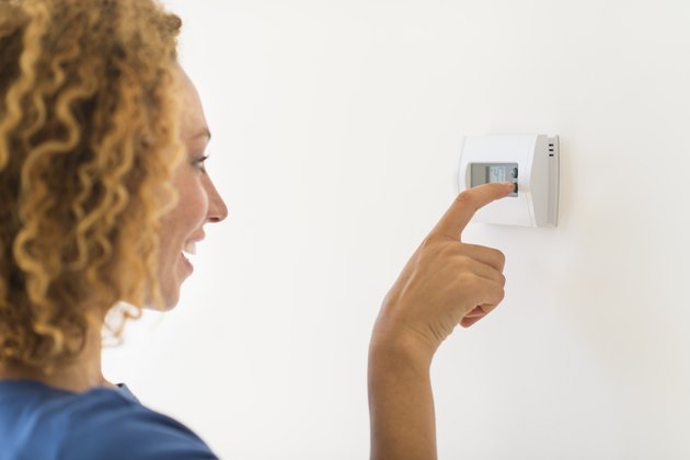 USA, New Jersey, Jersey City, Young woman setting air conditioning