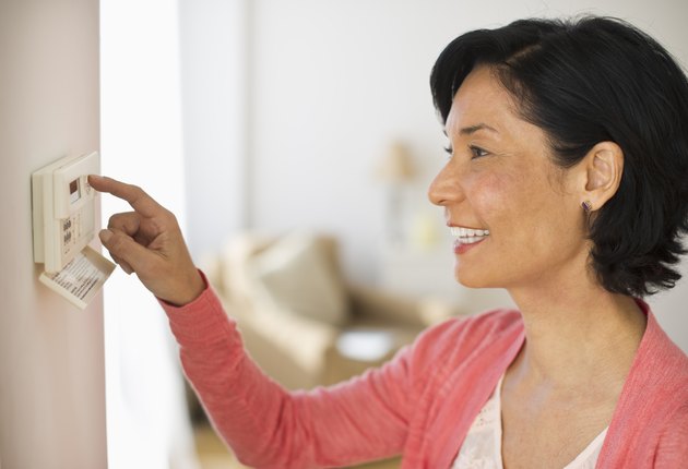 USA, New Jersey, Jersey City, Mature woman adjusting room temperature