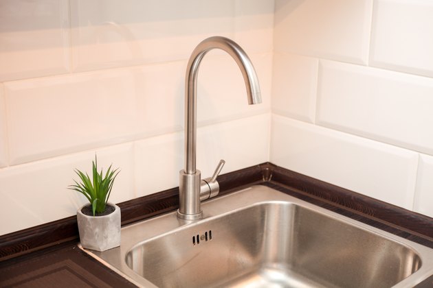 Modern kitchen with metal sink, white decorative wall