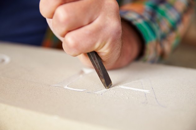 Close Up Of Stone Mason Working On Carving In Studio