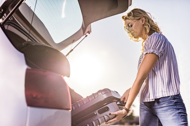 woman loading suitcase in trunk