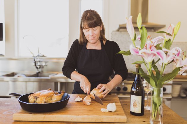 Woman cutting onion on cutting board at table