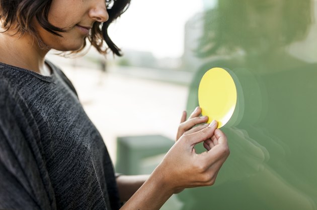 Close-up of woman attaching a sticker on a glass pane