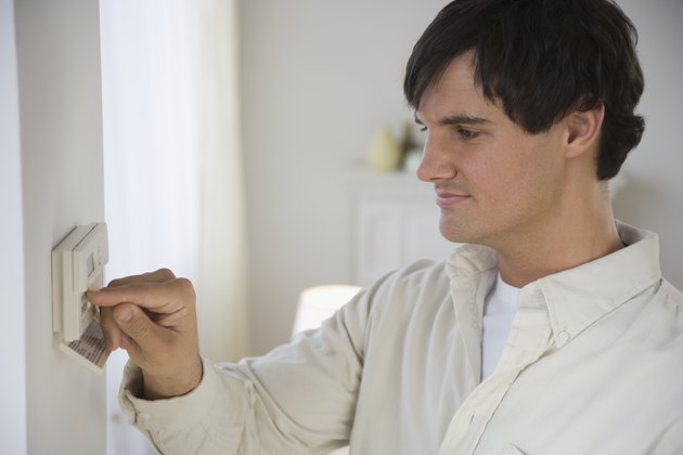 Man adjusting digital thermostat