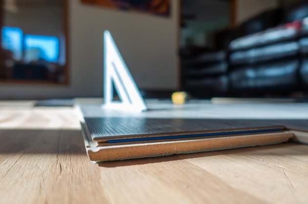 man installing engineered laminate wood floring indoor