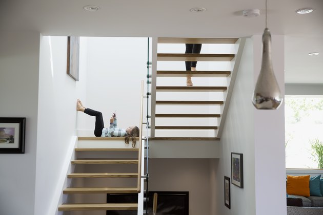 Girl using digital tablet laying on wooden stairway landing