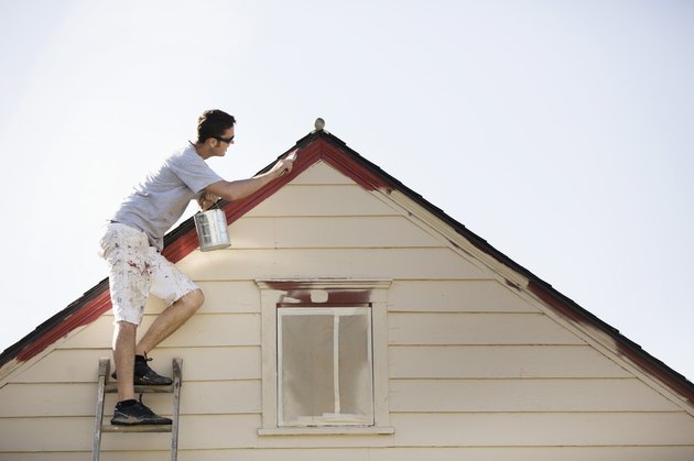 Caucasian man painting edge of roof