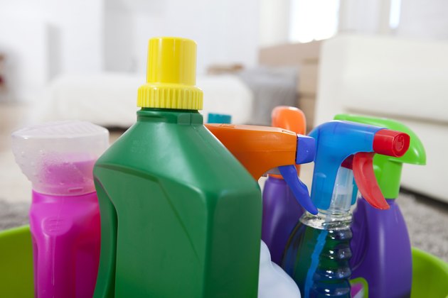 Colourful cleaning product plastic bottles and sprays on kitchen counter
