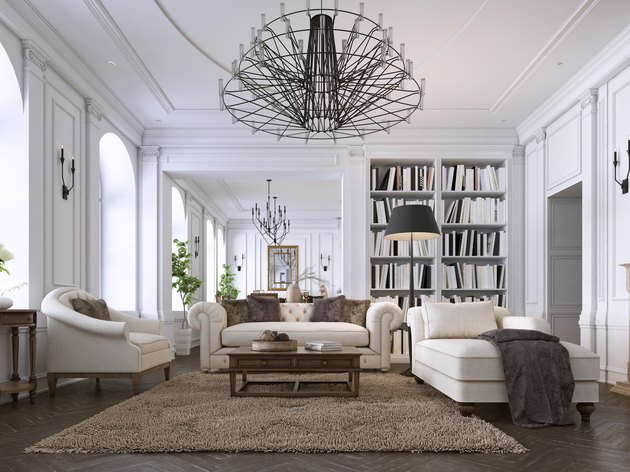 Luxury classic interior of living room and dining room with white furniture and metal chandeliers.