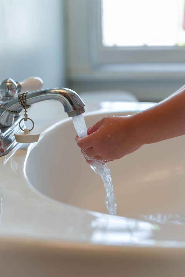 Closeup of child washing hands at bathroom sink - vertical