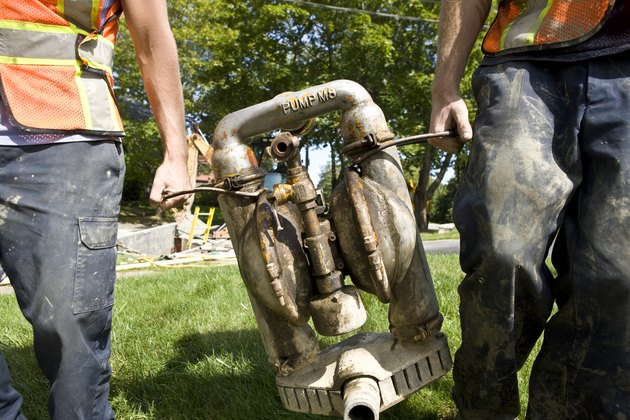 Two workers carrying water pump, mid section