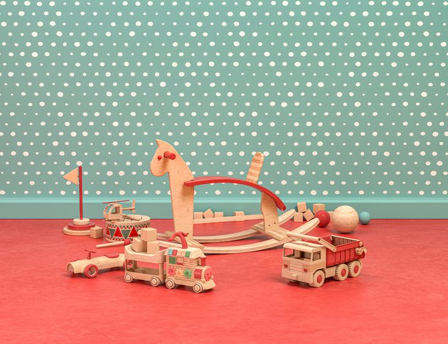Wood and plastic vintage style playroom with cockhorse and toys on green and red background, 3d Rendering
