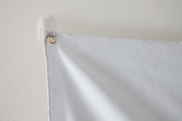 Projector screen hanging on adhesive wall hook