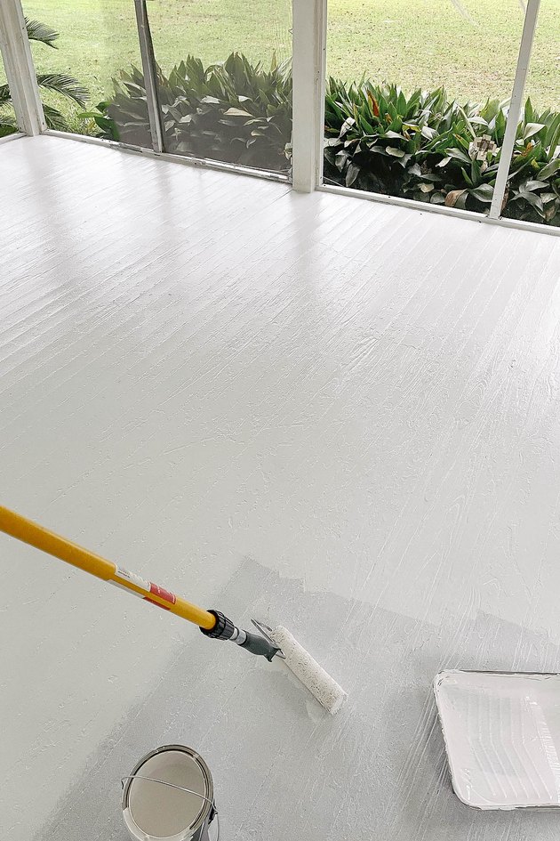 Rouler la première couche de peinture sur plancher de bois avec rallonge