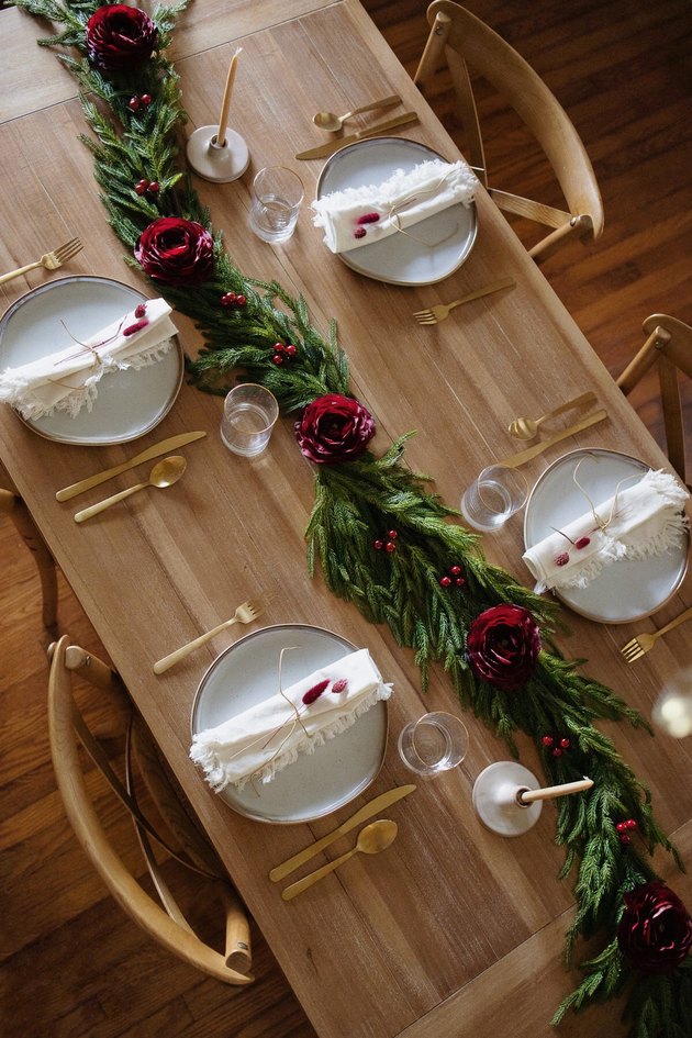 Holiday garland table runner decorated with burgundy ranunculus and berries
