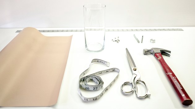 Leather sheet, measuring tape, shears, hammer, rivets, glass vase