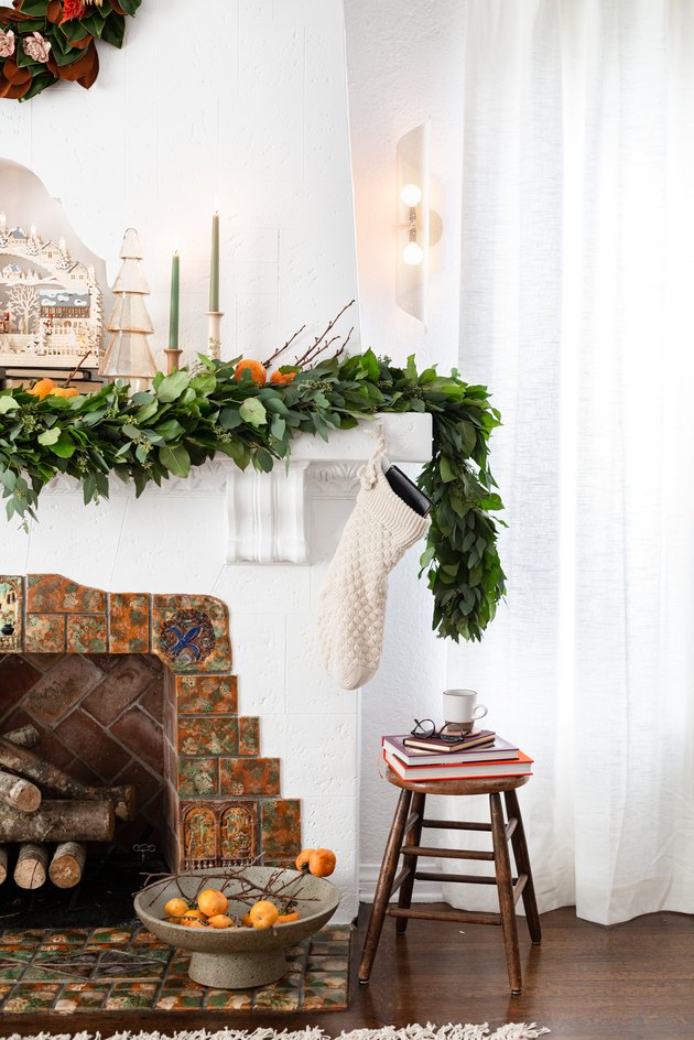 neutral Christmas decorations list with garland and candlesticks on mantel