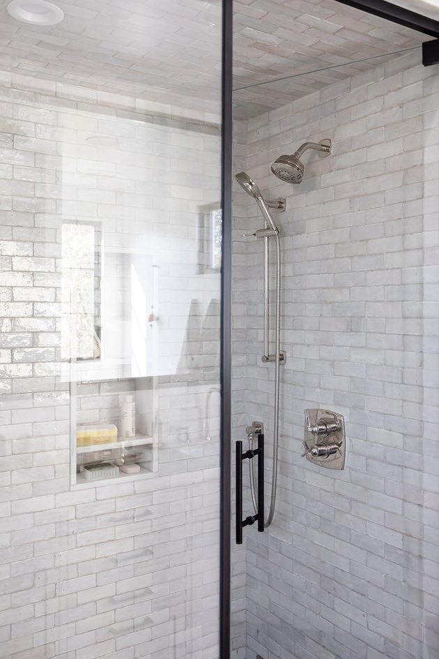 Glass shower doors with gray tiled walls