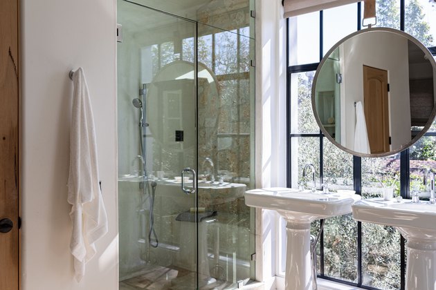 Bathroom with large windows, porcelain sinks, large mirror and glass door shower