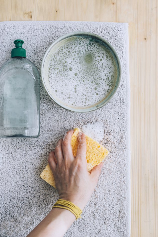 using a sponge and a solution of dish soap and water to clean carpet stain