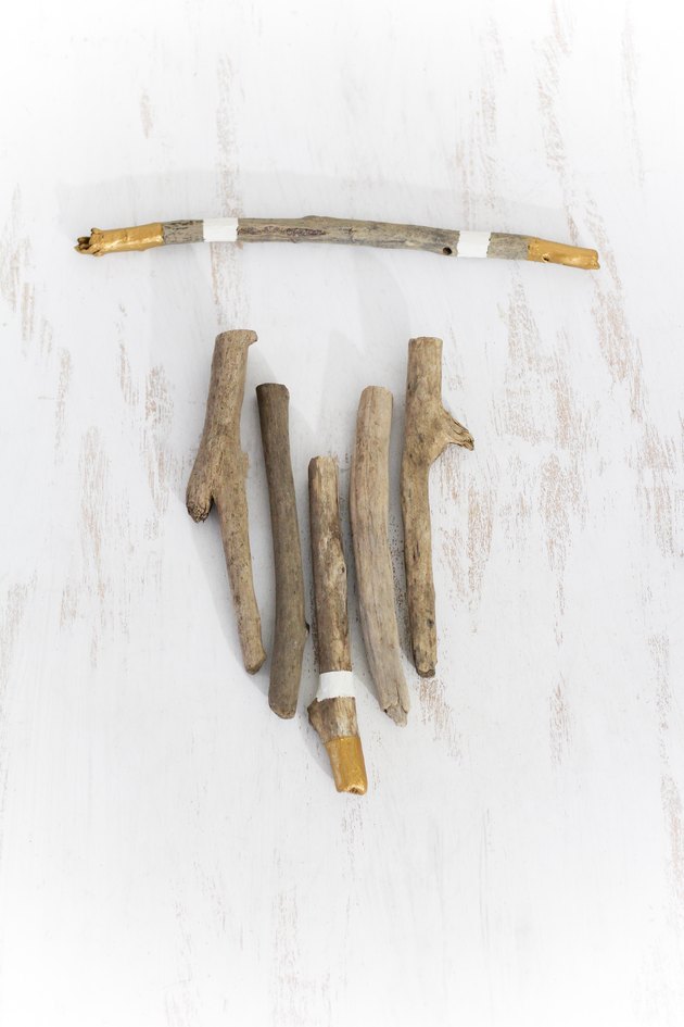 a diy wall hanging project in progress with a few sticks minimally painted