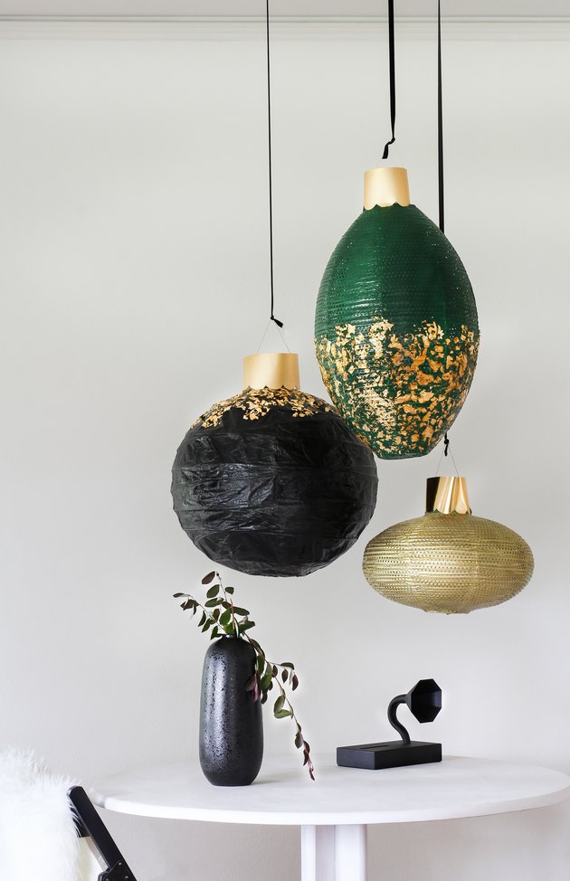 Black, green and gold lanterns above white table with black vase