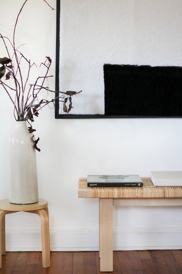 Minimalist black-white shearling wall art with bench, stool, and vase
