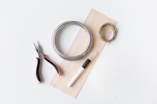 Wire cutter, wire, thread, pen, and tissue paper against a white background