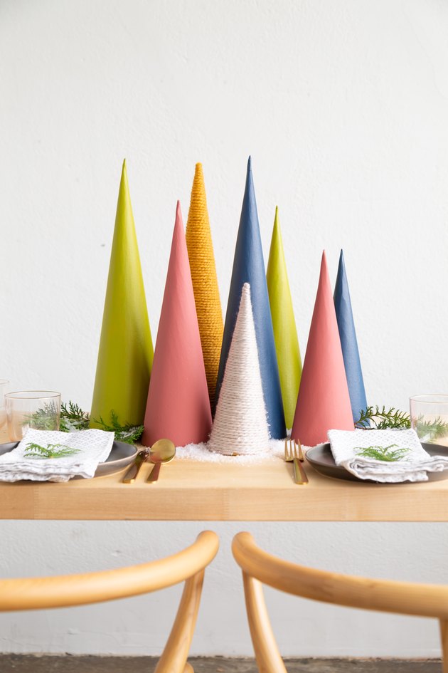 DIY Christmas decorations with a holiday centerpiece made of colorful cardboard cones, sprigs of greenery, and faux snow
