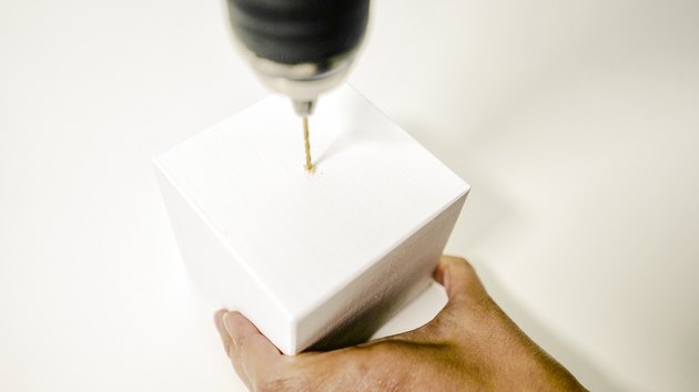 using power drill to drill a hole in the center of a wooden block