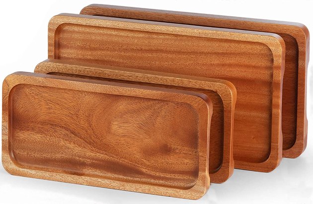 This set of four serving trays is made of solid wood with non-slip handle grips on each side. It boasts contemporary, natural platters with edges so that food doesn't slip off. 