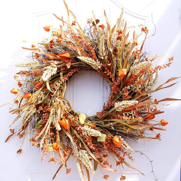 This elegant autumnal wreath might be faux, but it looks to be an all-natural arrangement of dried flowers, grains, and straw.
