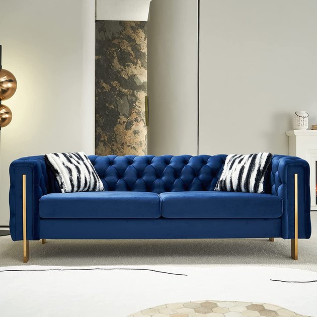 If you took a traditional chesterfield sofa, upholstered it with blue velvet instead of leather, and added some striking gold legs, you'd end up with this gorgeous piece of furniture.