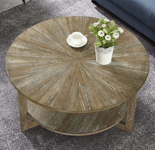 Complete your farmhouse living room with this round natural wood coffee table. Its two levels provide a generous amount of storage and tabletop space.
