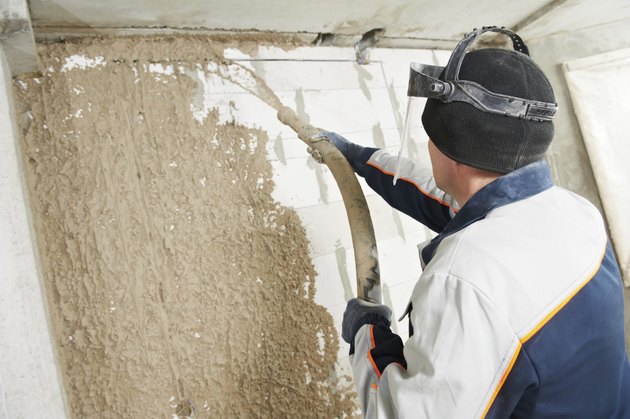 Plasterer at stucco work with liquid plaster